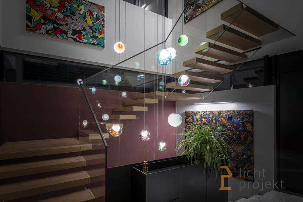 Kugelförmige, bunte Hängeleuchten, die einen Treppenaufgang in einem Haus ausschmücken